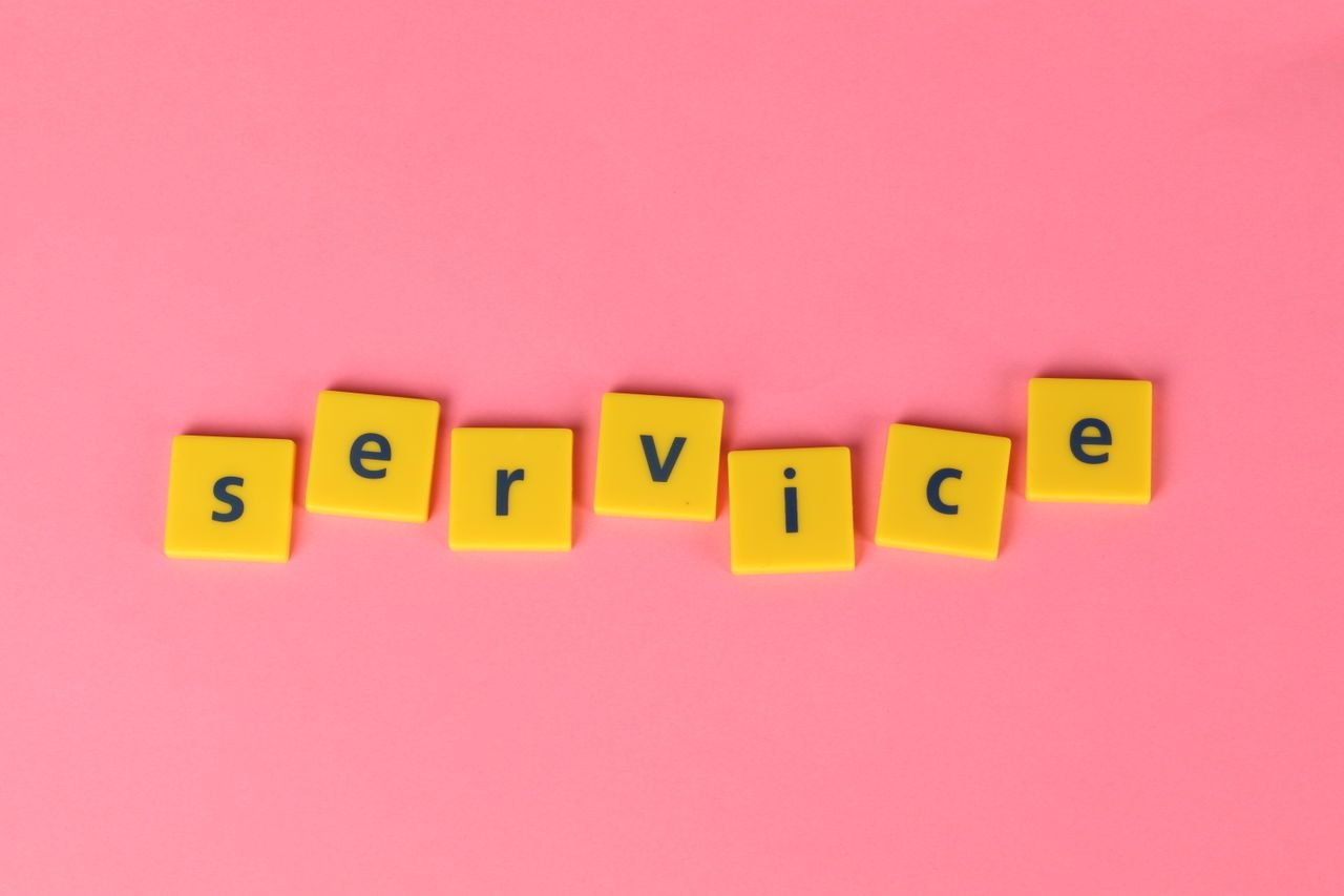 Yellow tiles spelling the word 'service' on a pink background, visually appealing design.