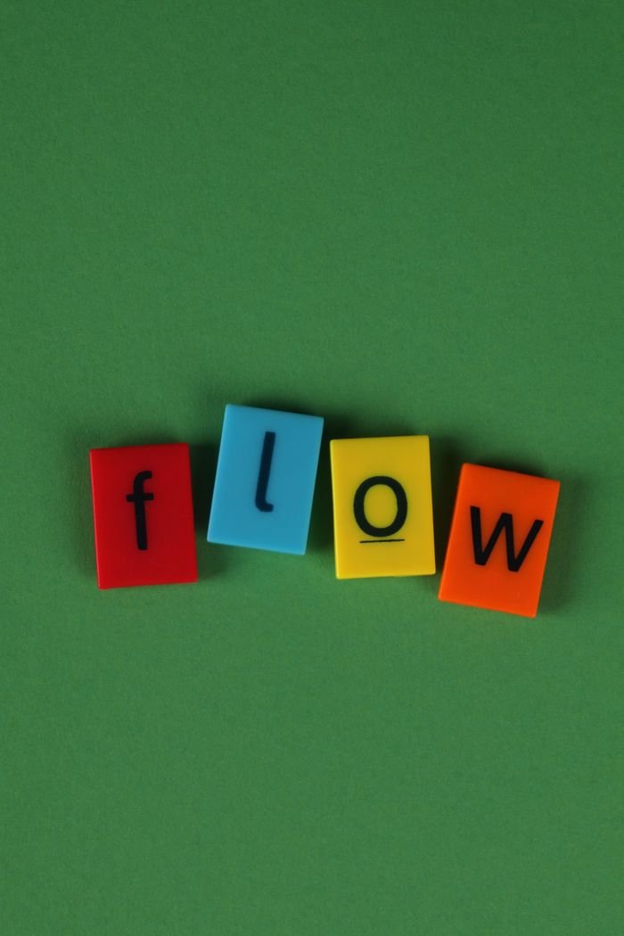 Vivid alphabet blocks spell 'Flow' on a vibrant green surface.